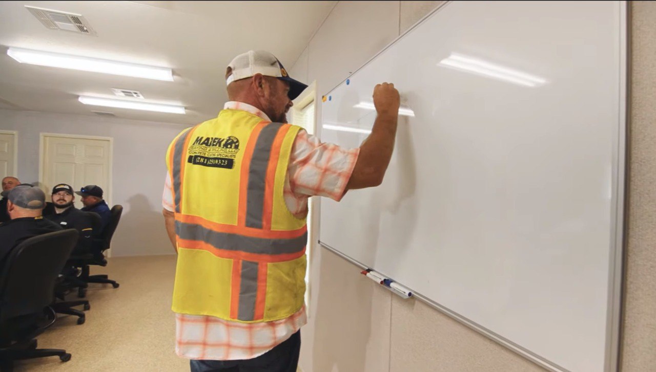 A Marek foreman leading a crew briefing at a whiteboard